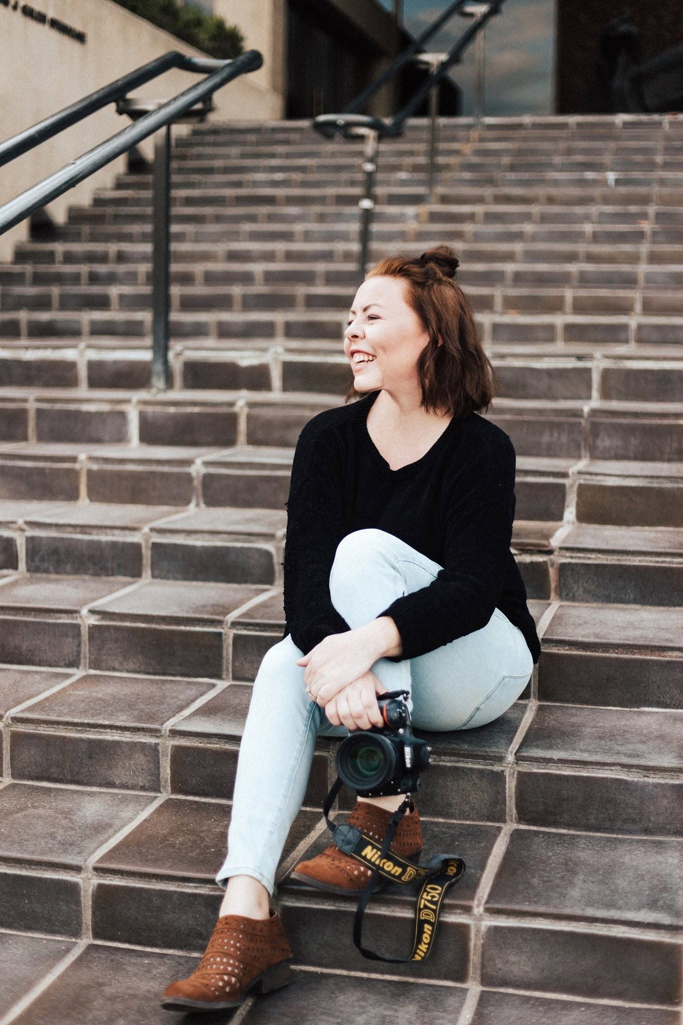 Laura sitting on outdoor steps with her Nikon camera